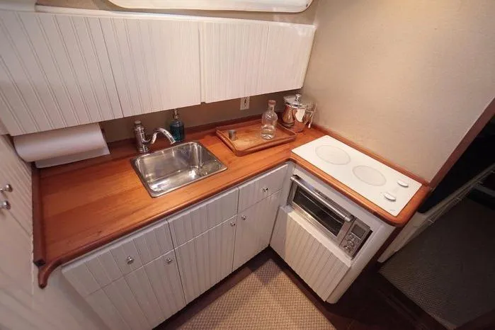 Faith Yacht Photos Pics Compact galley kitchen in 2003 Huckins Atlantic 44 yacht with sink, stove, and wooden countertop.