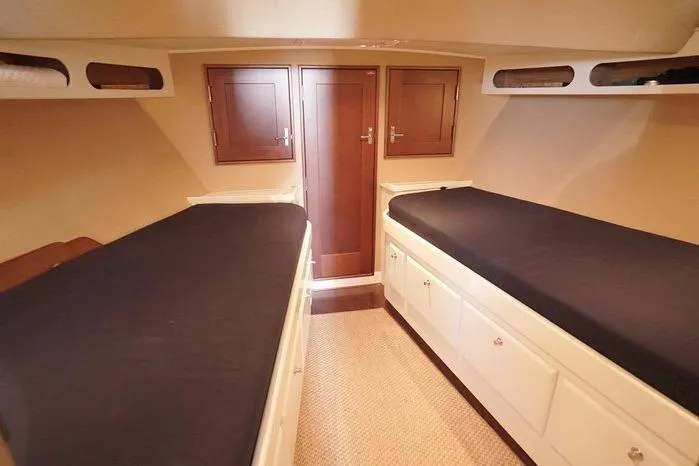 Faith Yacht Photos Pics Cabin interior of 2003 Huckins Atlantic 44 with twin beds and wooden cabinetry.