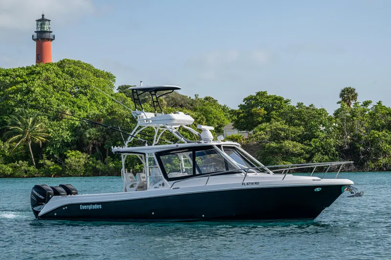 Kirby 107 Yacht Photos Pics 2014 Everglades 350LX boat cruising near a lush shoreline with a lighthouse in the background.