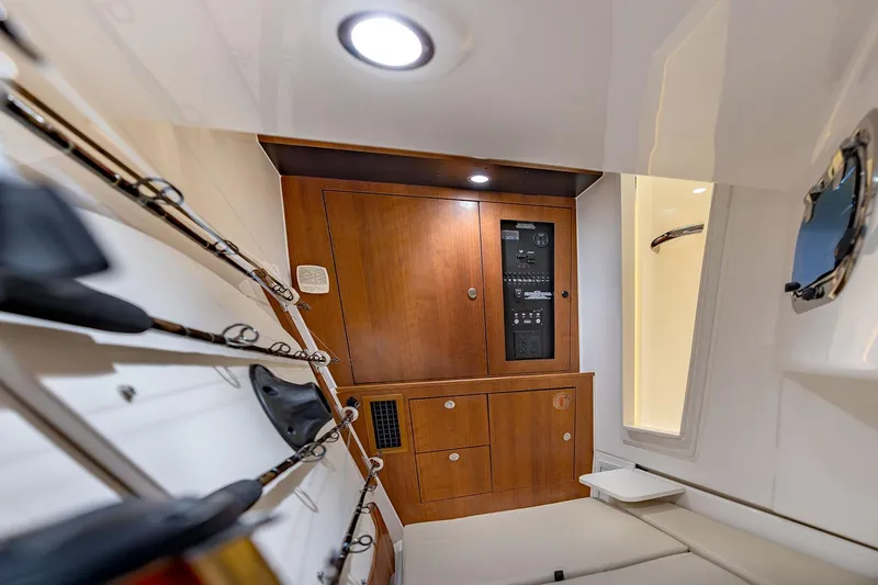  Yacht Photos Pics Manufacturer Provided Image: 2025 Pursuit DC 326 Dual Console cabin interior with wooden cabinetry and fishing rod storage.