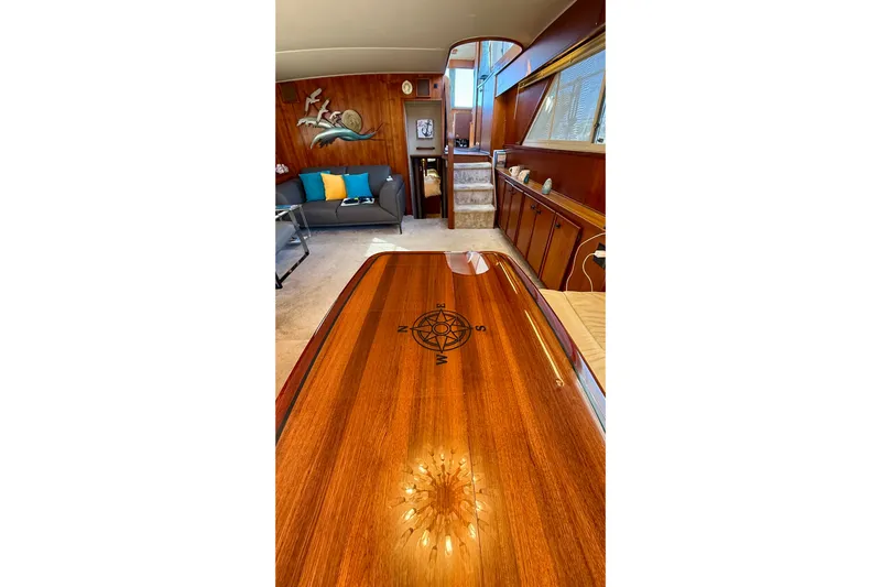 Moonlight Mist Yacht Photos Pics Luxurious 1987 Chris-Craft 500 Constellation yacht interior with polished wood table and compass design.