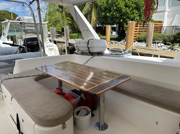 Bat Ha Yam Yacht Photos Pics Leopard 47 catamaran cockpit with wooden table and cushioned seating, docked at marina.