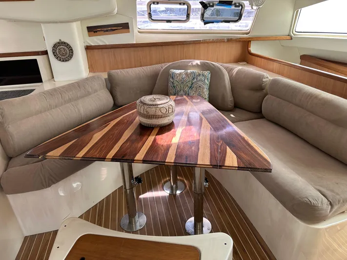 Bat Ha Yam Yacht Photos Pics Cozy interior of 2001 Leopard 47 yacht with elegant wood table and cushioned seating.