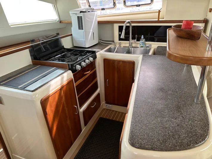 Bat Ha Yam Yacht Photos Pics Leopard 47 yacht kitchen, 2001 model, featuring stove, sink, and wooden cabinetry.