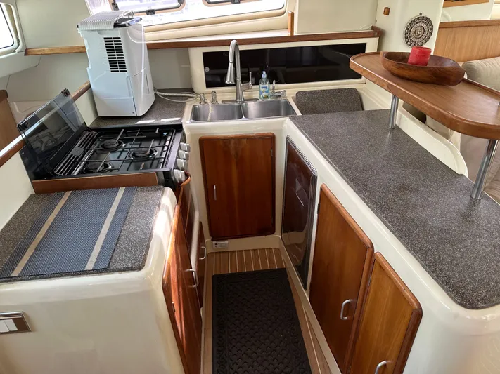 Bat Ha Yam Yacht Photos Pics Compact kitchen in a 2001 Leopard 47 yacht with wooden cabinets and modern appliances.
