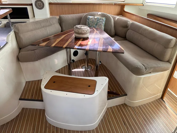 Bat Ha Yam Yacht Photos Pics Cozy seating area on a 2001 Leopard 47 yacht with wooden table and cushions.