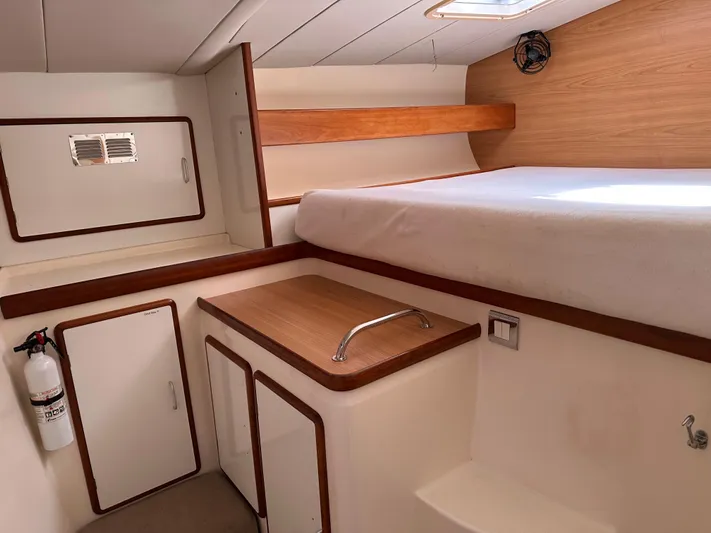 Bat Ha Yam Yacht Photos Pics Interior of 2001 Leopard 47 yacht cabin with bed, storage, and fire extinguisher.