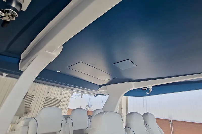  Yacht Photos Pics Interior view of 2025 Intrepid 43 Nomad SE boat with blue ceiling and white seating.