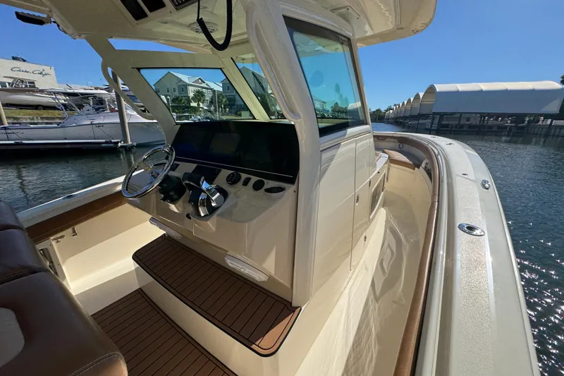  Yacht Photos Pics 2019 Scout 355 LXF boat interior with helm, docked in marina under clear sky.