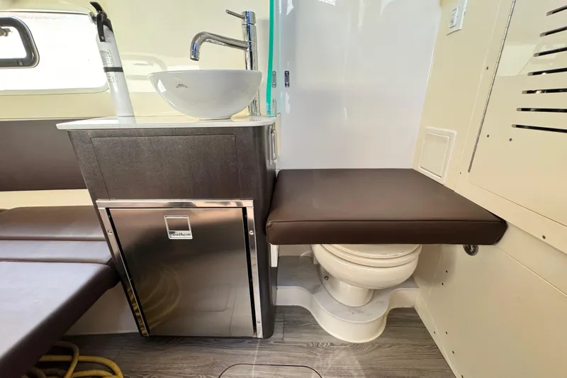  Yacht Photos Pics 2019 Scout 355 LXF boat interior with sink, seating, and compact toilet.