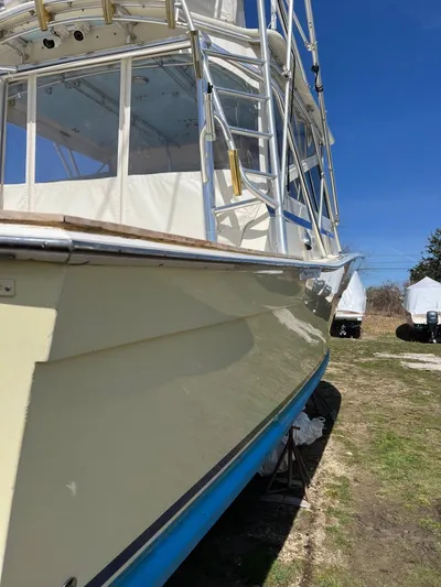 Carolina Girl Yacht Photos Pics 1985 Viking Express boat with cream hull and blue bottom, docked on land under clear sky.