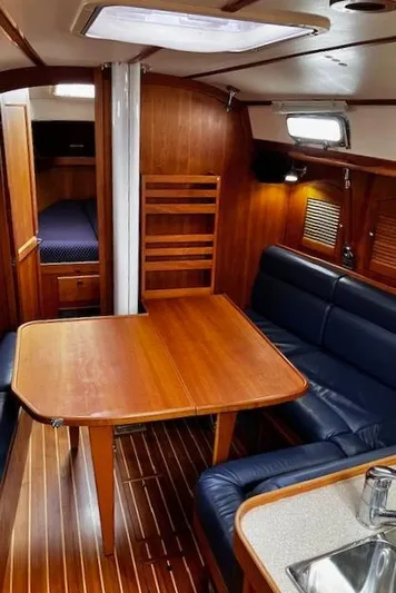 Indigo Yacht Photos Pics Interior of a 2002 Sabre 362 sailboat with wooden dining area and blue seating.