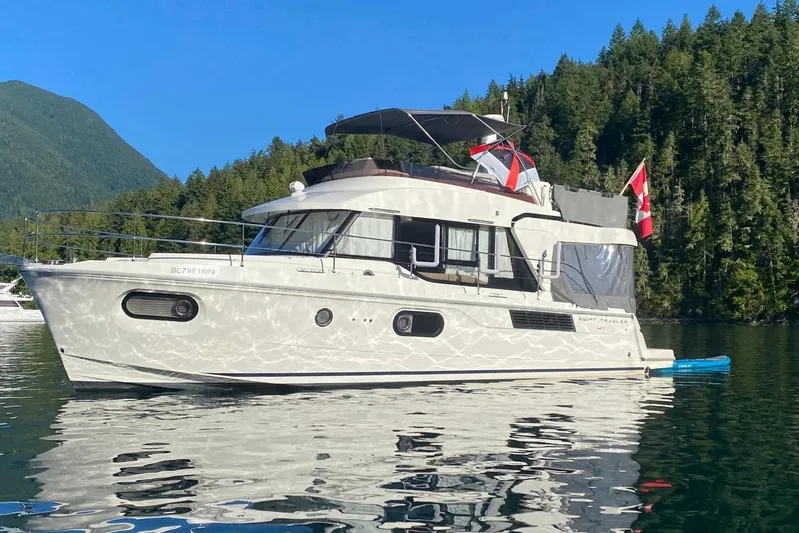 Changes In Latitude Yacht Photos Pics 2022 Beneteau Swift Trawler 41 Fly on serene water, surrounded by lush forest.