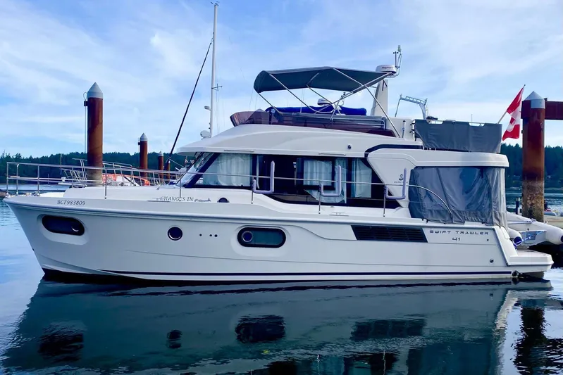 Changes In Latitude Yacht Photos Pics 2022 Beneteau Swift Trawler 41 Fly moored at a marina, reflecting on calm water.