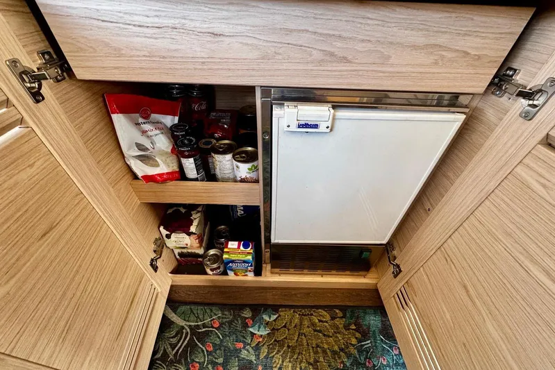 Changes In Latitude Yacht Photos Pics Pantry storage in 2022 Beneteau Swift Trawler 41 Fly, featuring shelves with canned goods.
