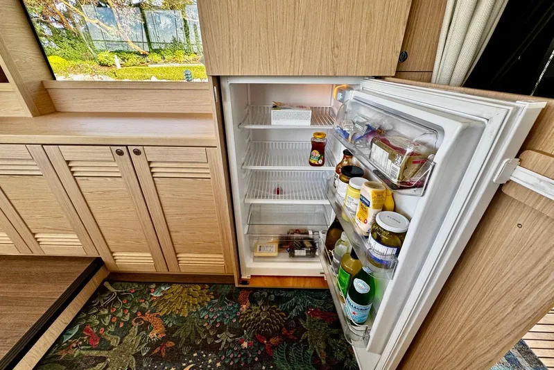 Changes In Latitude Yacht Photos Pics Open fridge in 2022 Beneteau Swift Trawler 41 Fly, stocked with various food items.