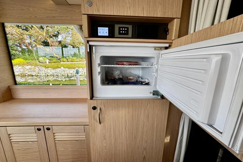 Changes In Latitude Yacht Photos Pics Open freezer in 2022 Beneteau Swift Trawler 41 Fly, showcasing interior storage.