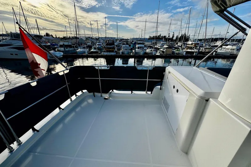 Changes In Latitude Yacht Photos Pics 2022 Beneteau Swift Trawler 41 Fly at marina, Canadian flag, clear sky, calm water.