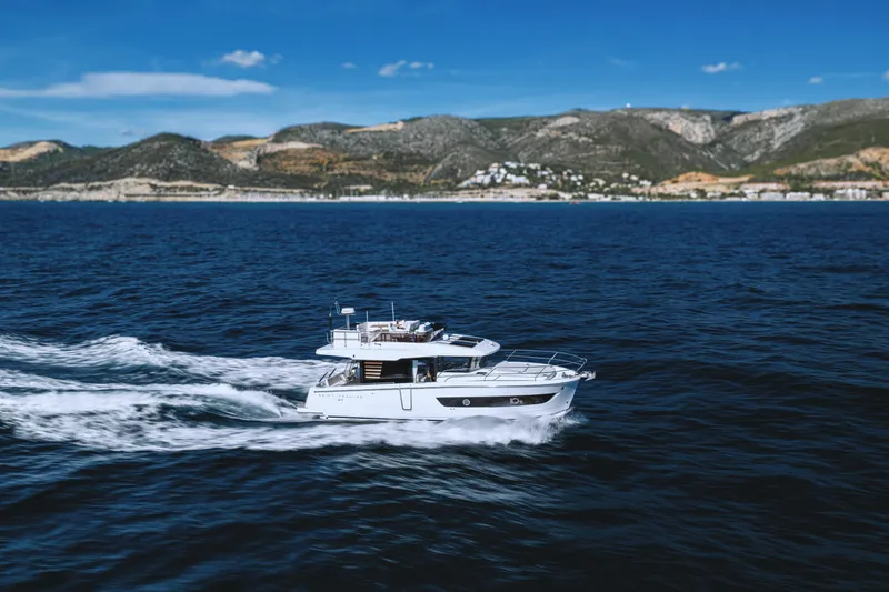  Yacht Photos Pics 2026 Beneteau Swift Trawler 37 cruising on open sea with scenic mountain backdrop.
