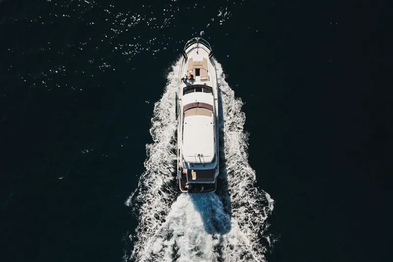  Yacht Photos Pics Aerial view of 2022 Prestige 590 yacht cruising on dark blue water.