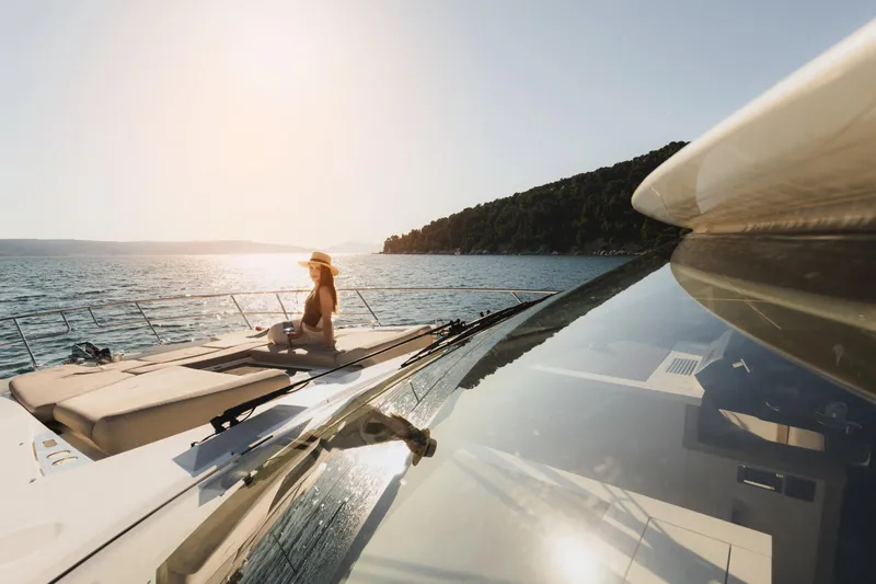  Yacht Photos Pics Woman relaxing on a 2022 Prestige 590 yacht, enjoying a sunny day at sea.