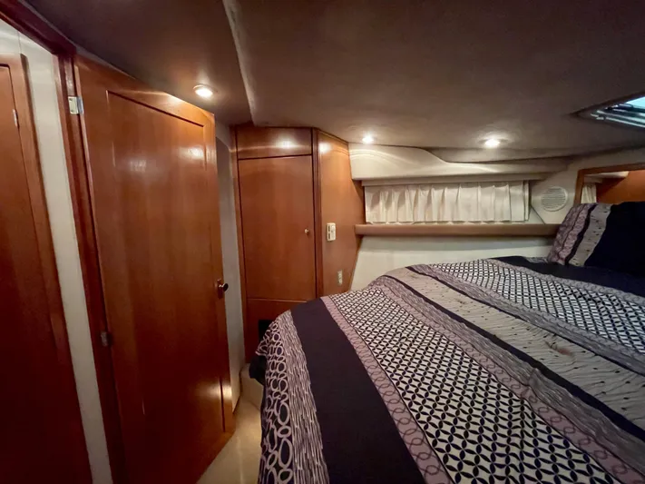 Casting Shadows Yacht Photos Pics Cozy bedroom interior of 1998 Bayliner 3988 Command Bridge Motoryacht with patterned bedding and wood paneling.