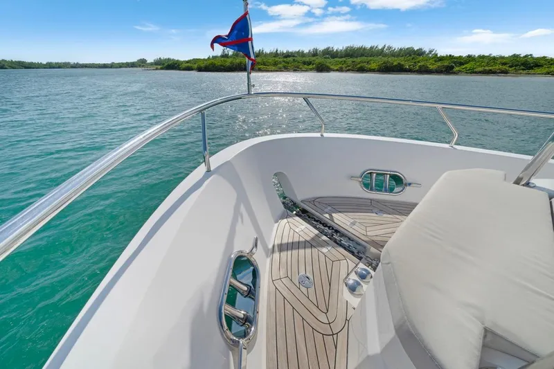 Valiant Yacht Photos Pics Bow view of 2022 Horizon E81 yacht on serene water with lush shoreline.