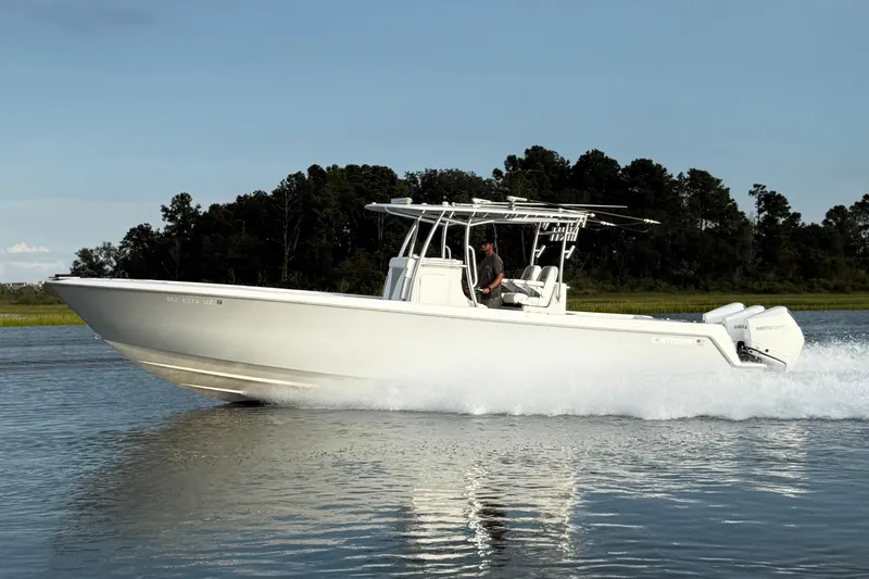  Yacht Photos Pics 2022 Contender 35 ST boat cruising on a calm lake with forested background.