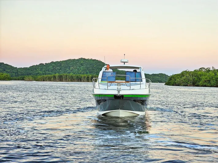 Custom Order Yours Today! Yacht Photos Pics 2025 Hanover 375 Outboard cruising on serene water with lush green hills in the background.