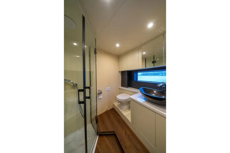  Yacht Photos Pics Modern yacht bathroom with glass shower, vessel sink, and wood flooring in Phantom Spook 62, 2025 model.