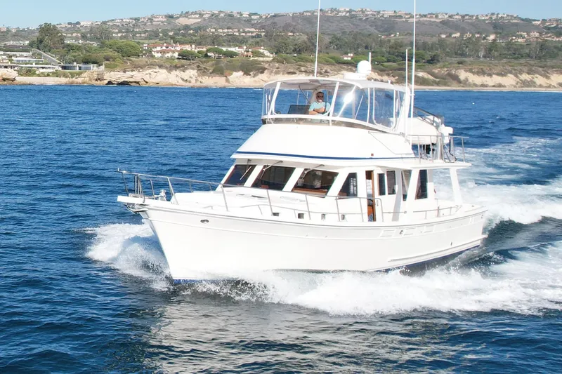 Treasure Yacht Photos Pics Offshore Yachts 48 Sedan 1997 cruising on blue ocean near scenic coastline.