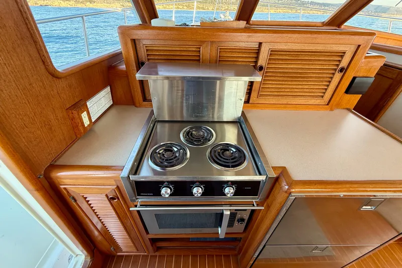 Treasure Yacht Photos Pics 1997 Offshore Yachts 48 Sedan kitchen with stove and wooden cabinetry.