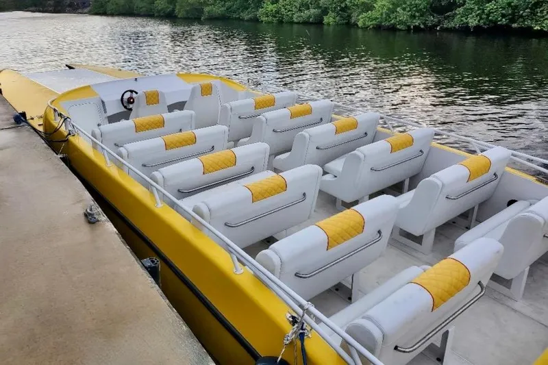  Yacht Photos Pics 2005 Thriller Powerboats Super Cat 55 with yellow and white seating, docked by a river.