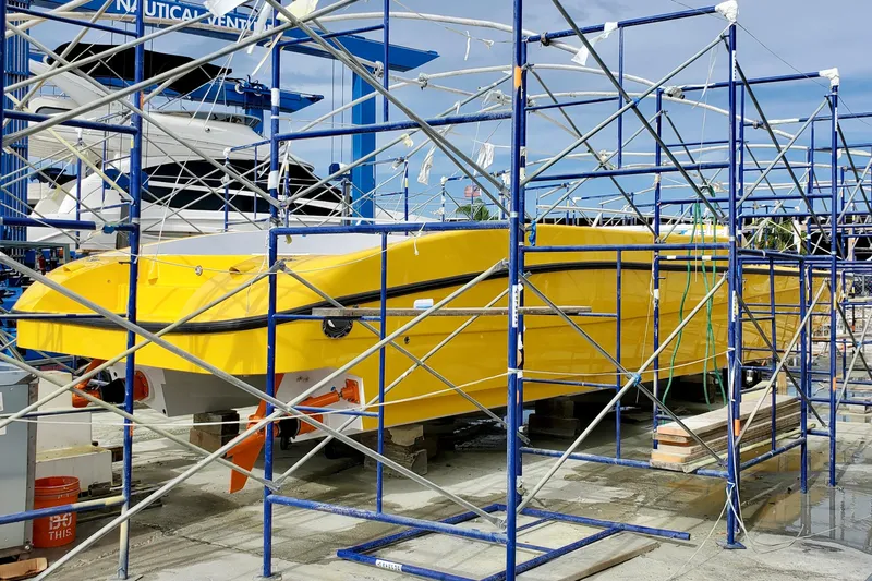  Yacht Photos Pics Yellow 2005 Thriller Powerboats Super Cat 55 under scaffolding at a marina.