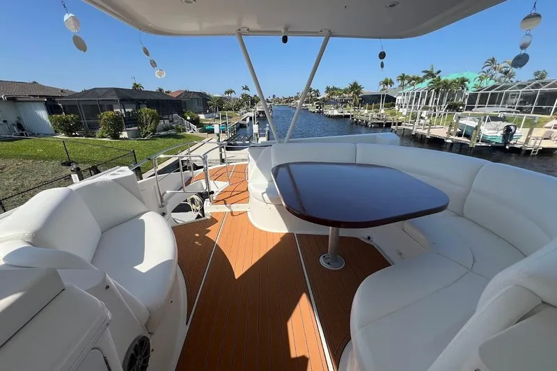 Our Trade Yacht Photos Pics Luxurious 2006 Carver 56 Voyager yacht deck with seating and table, docked by waterfront homes.