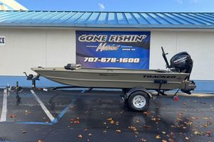 2026 Tracker Grizzly 1654 T Sportsman boat on trailer, parked outside a fishing store.