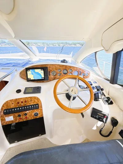 Four Shore Yacht Photos Pics Interior view of 2002 Azimut 42 yacht cockpit with navigation controls and wooden steering wheel.