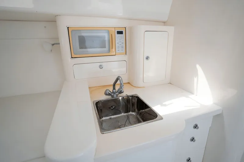  Yacht Photos Pics Compact kitchenette in a 2005 Intrepid 348 WA boat with sink and microwave.
