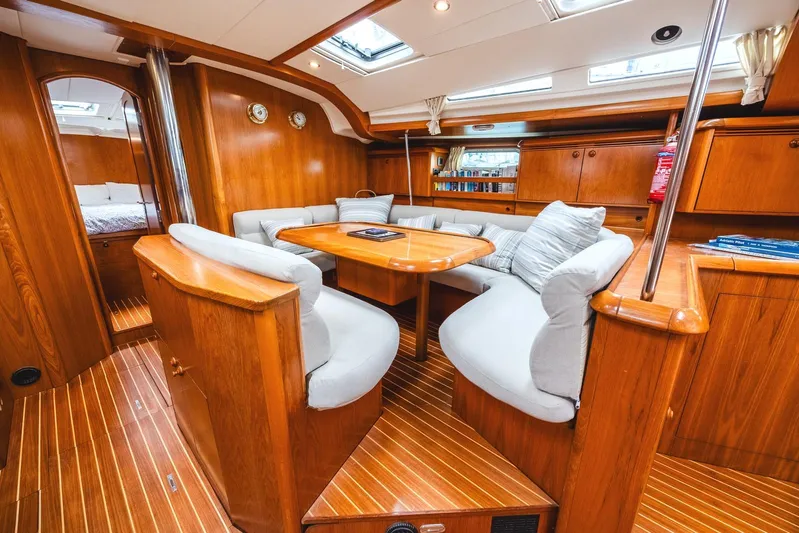  Yacht Photos Pics Luxurious interior of 2006 Jeanneau Sun Odyssey 49 sailboat with wooden furnishings and cozy seating.