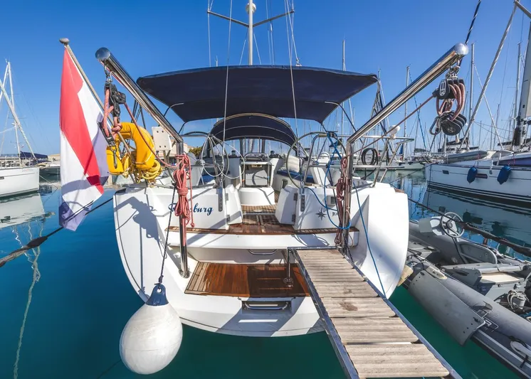  Yacht Photos Pics 2006 Jeanneau Sun Odyssey 49 sailboat docked in marina, rear view with flag and canopy.