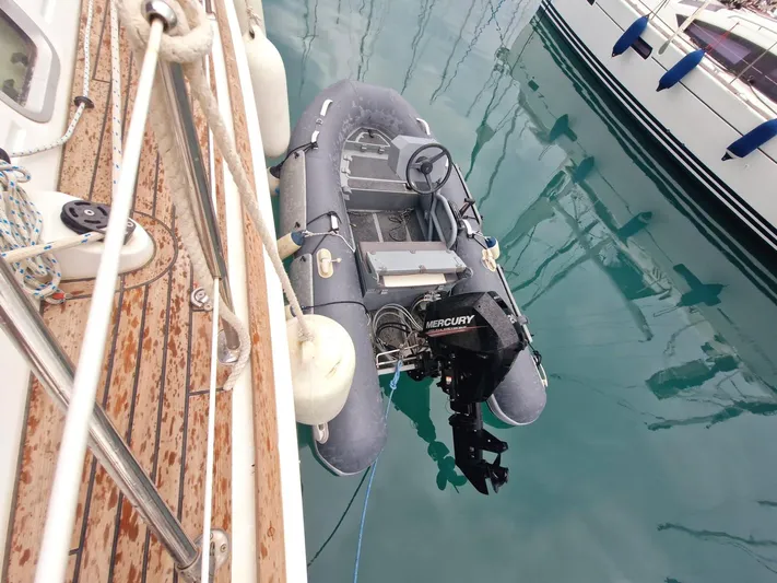  Yacht Photos Pics Inflatable dinghy with Mercury outboard motor beside Jeanneau Sun Odyssey 49, 2006 model, in marina.