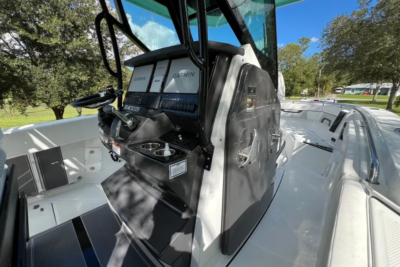  Yacht Photos Pics 2023 Blackfin 272 boat cockpit with Garmin displays and steering wheel, surrounded by trees.