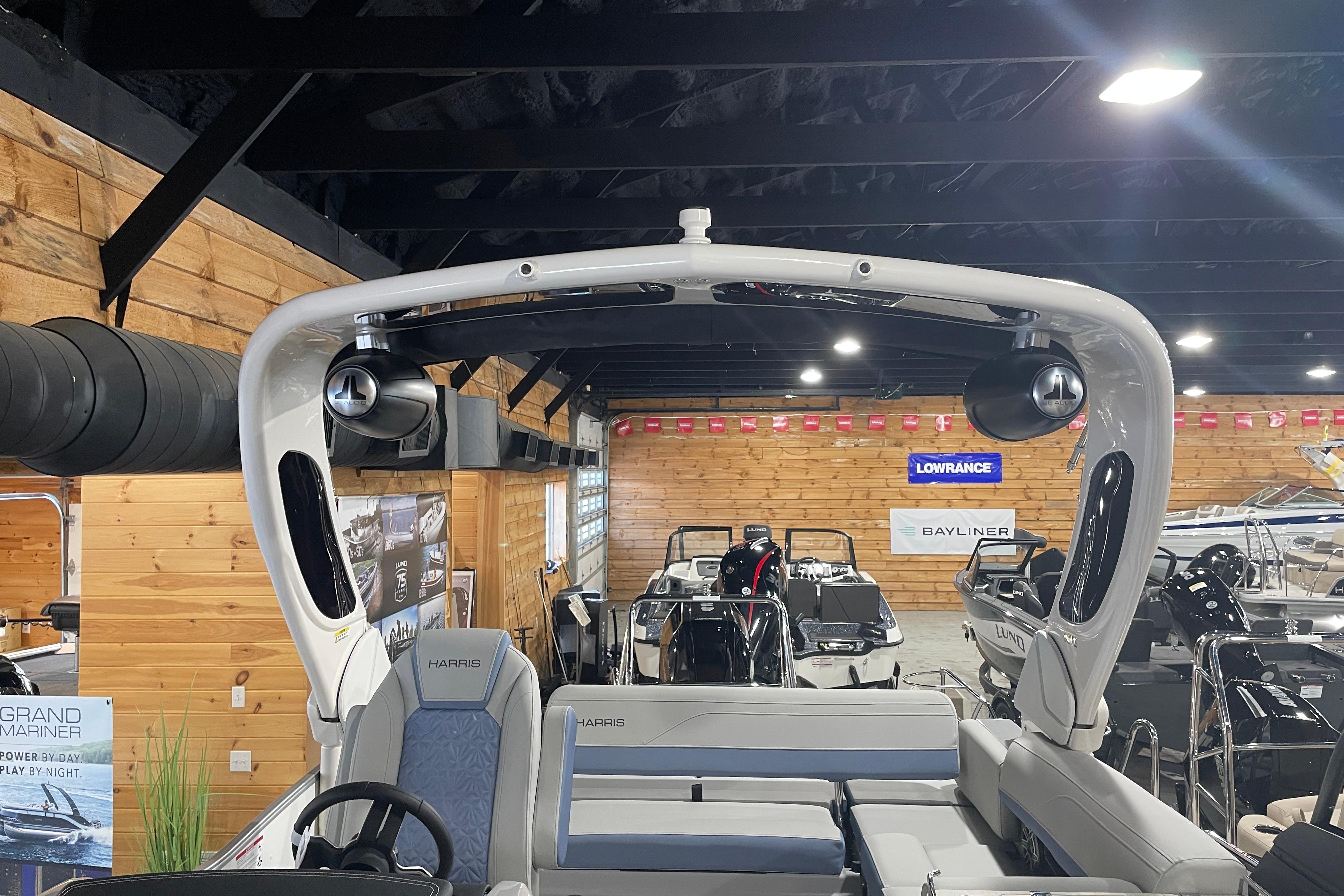 2026 Harris Grand Mariner SEL 250 boat interior in showroom with wooden walls and lighting.