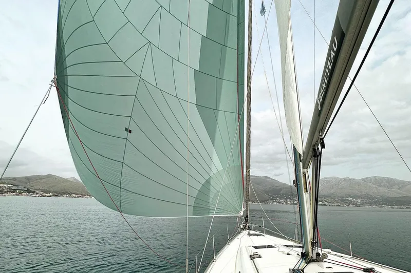 Margaret Yacht Photos Pics 2014 Beneteau Oceanis 48 sailing with spinnaker on open water, coastal mountains in background.