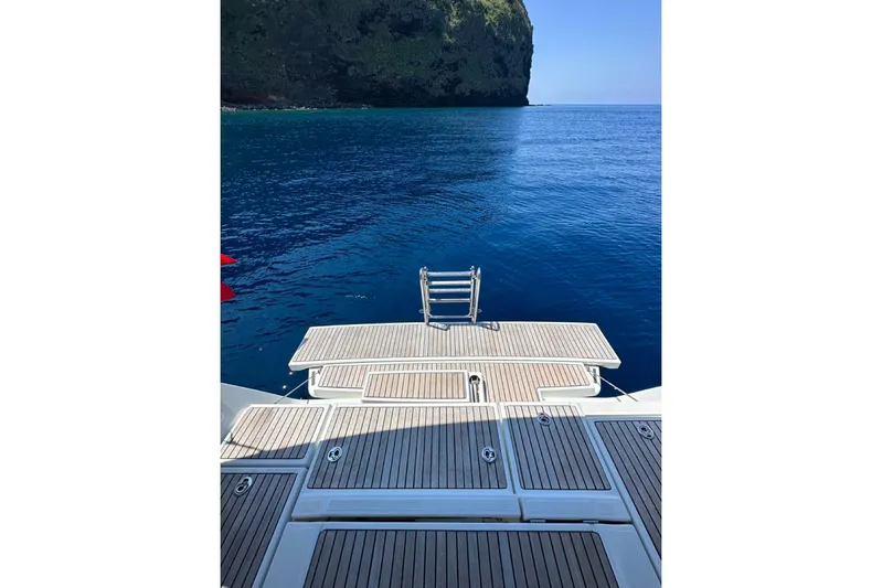Margaret Yacht Photos Pics Beneteau Oceanis 48 yacht deck overlooking serene blue ocean and rocky cliff, 2014 model.