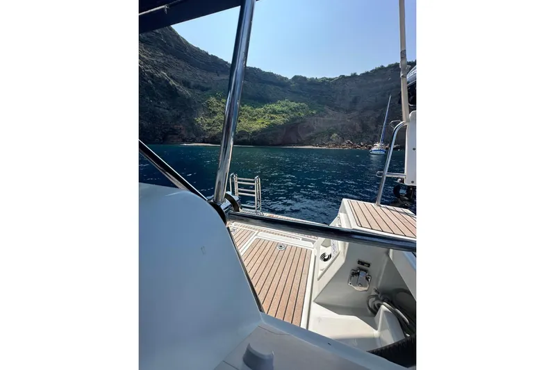 Margaret Yacht Photos Pics Beneteau Oceanis 48 sailboat, 2014 model, docked near rocky coastline with clear blue water.