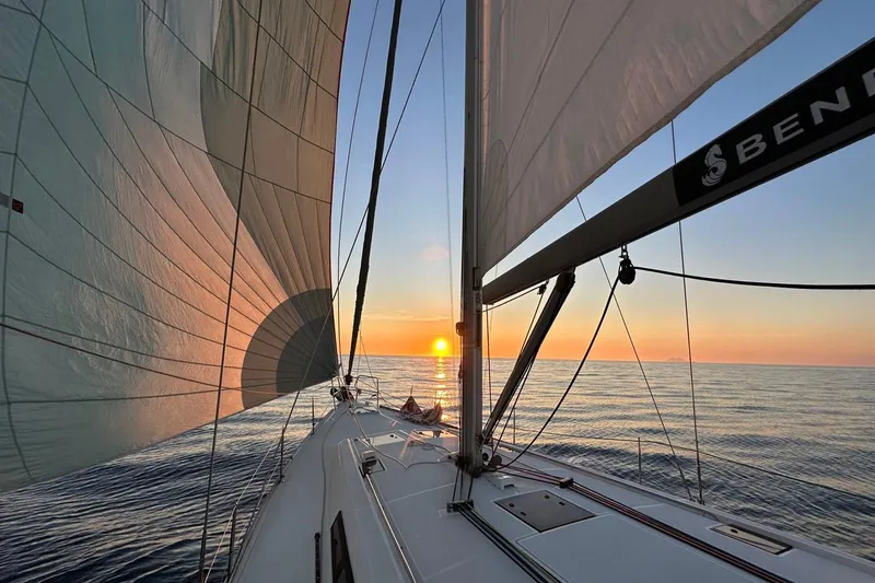Margaret Yacht Photos Pics 2014 Beneteau Oceanis 48 sailing at sunset, calm sea, vibrant sky.
