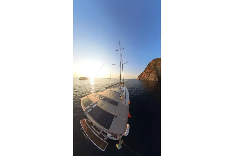 Margaret Yacht Photos Pics 2014 Beneteau Oceanis 48 yacht at sunset near rocky coastline.