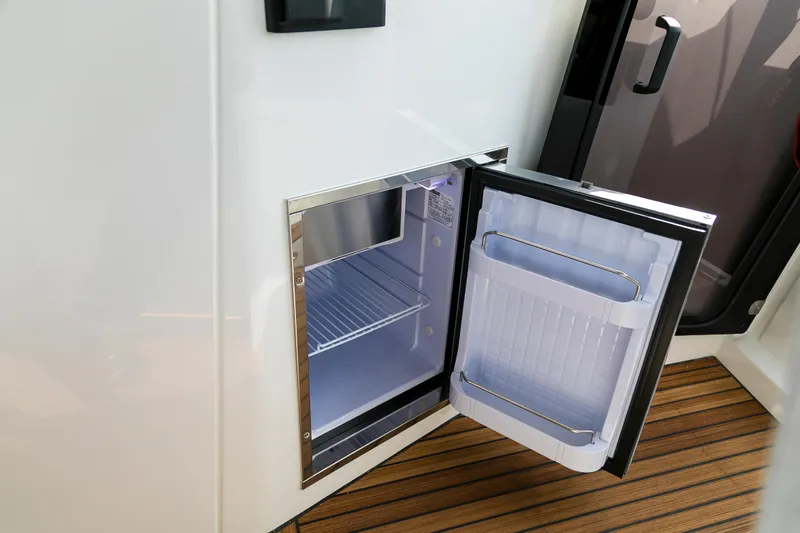  Yacht Photos Pics Open mini fridge on 2025 Beneteau Gran Turismo 45 yacht, showcasing interior storage space.