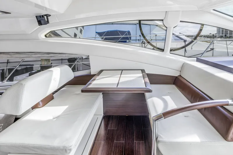 Liquidity Yacht Photos Pics Interior seating area of 2012 Azimut 48 Flybridge yacht with white cushions and wooden table.